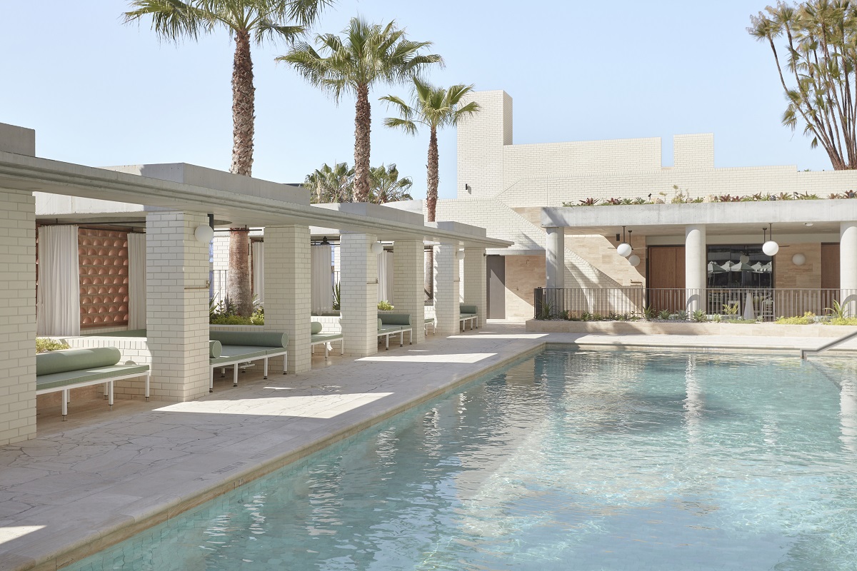 The Calile pool deck with green cabanas and palms.