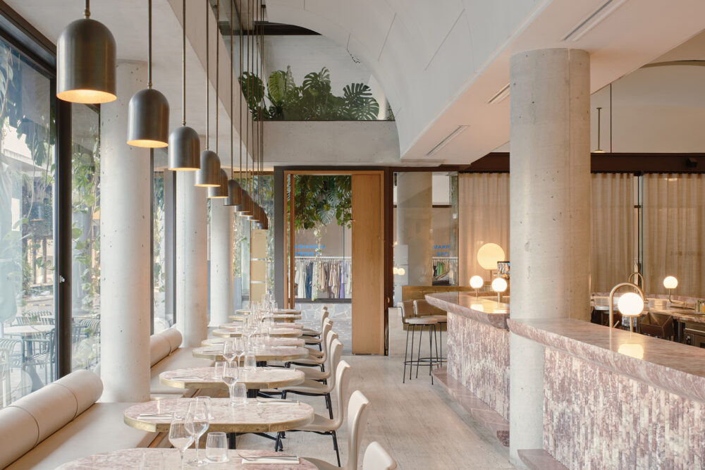 The restaurant interior with marble counter, brass pendants and concrete columns.